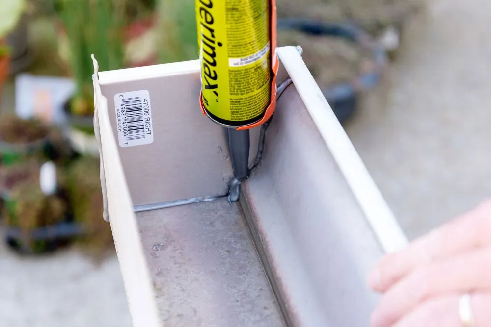Найкращі герметики для жолобів 2026: експертний тест 41 Person squeeze a gray caulk sealant onto the seams of a white gutter