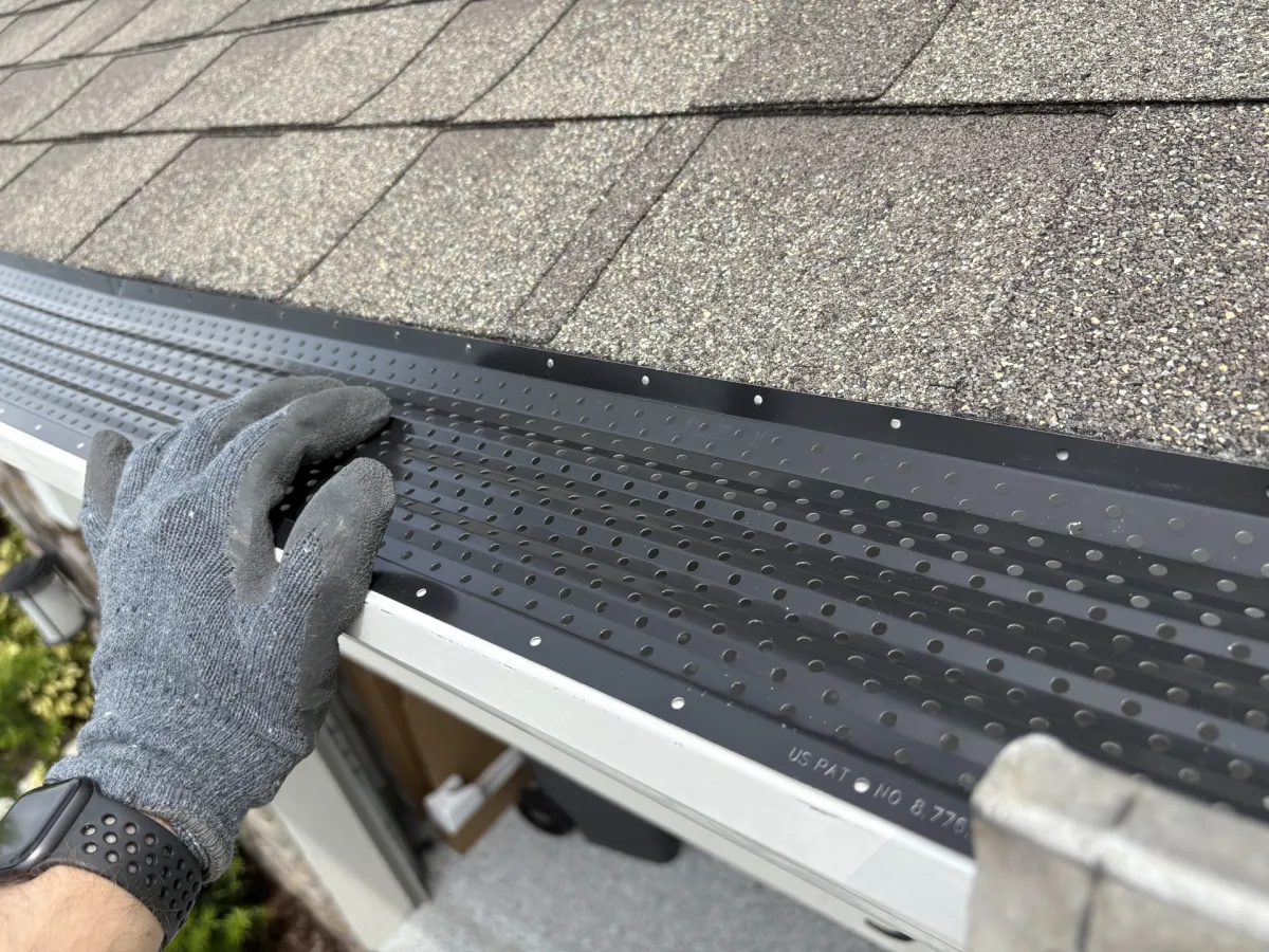 Людина встановлює чорний LeafTek Gutter Guard